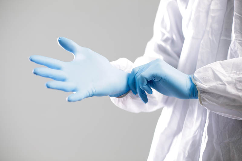 Doctor,In,A,Protective,Suit,Puts,On,Blue,Rubber,Gloves