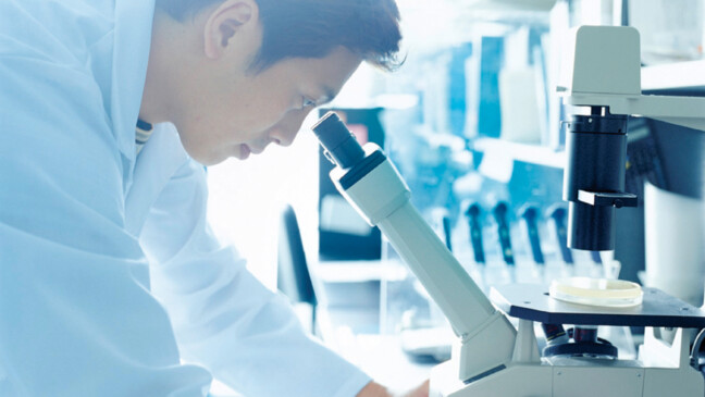 Research scientist looking into microscope, side view
