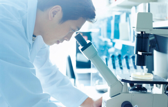 Research scientist looking into microscope, side view